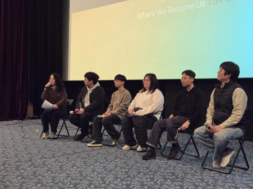 극장 공간 앞 무대 위에 여섯 명의 사람이 앉아 마이크를 잡고 이야기를 하고 있다. 무대 뒤 스크린에는 무지개색 배경 위 검정색 박스에 실시간 문자통역 글자가 흰색으로 비치고 있다.
: 30회 인천인권영화제 <우리는 광장에서>대화의 시간 풍경